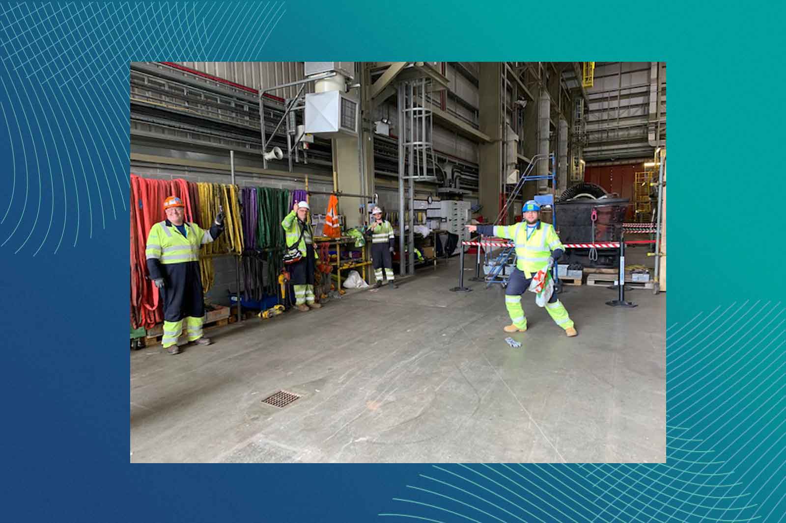 Workers in high-visibility clothing are engaged in an industrial setting, with safety equipment and ropes visible in the background.