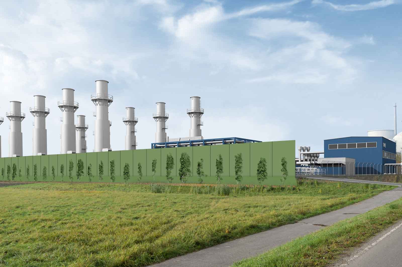 A modern industrial facility with tall chimneys, surrounded by a green privacy wall and grassy areas.