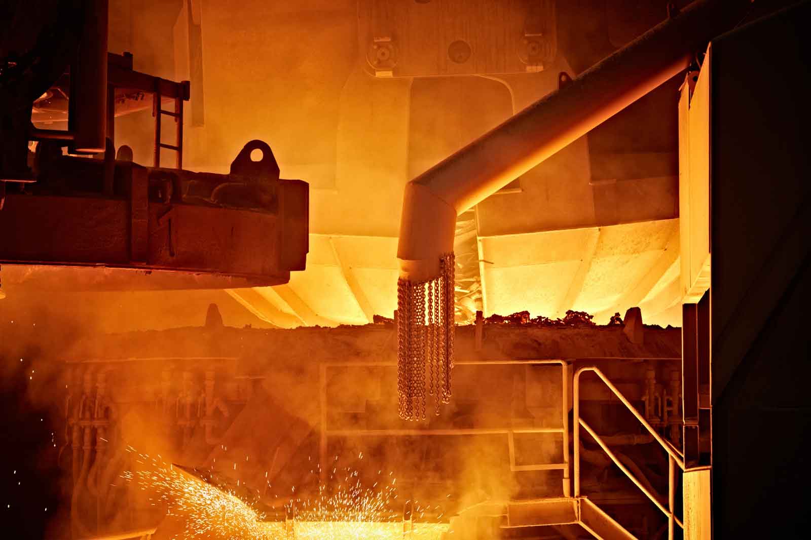 Eine industrielle Szene mit glühendem Metall, Rauch und Funken, die von einem Schmelzofen ausgehen.