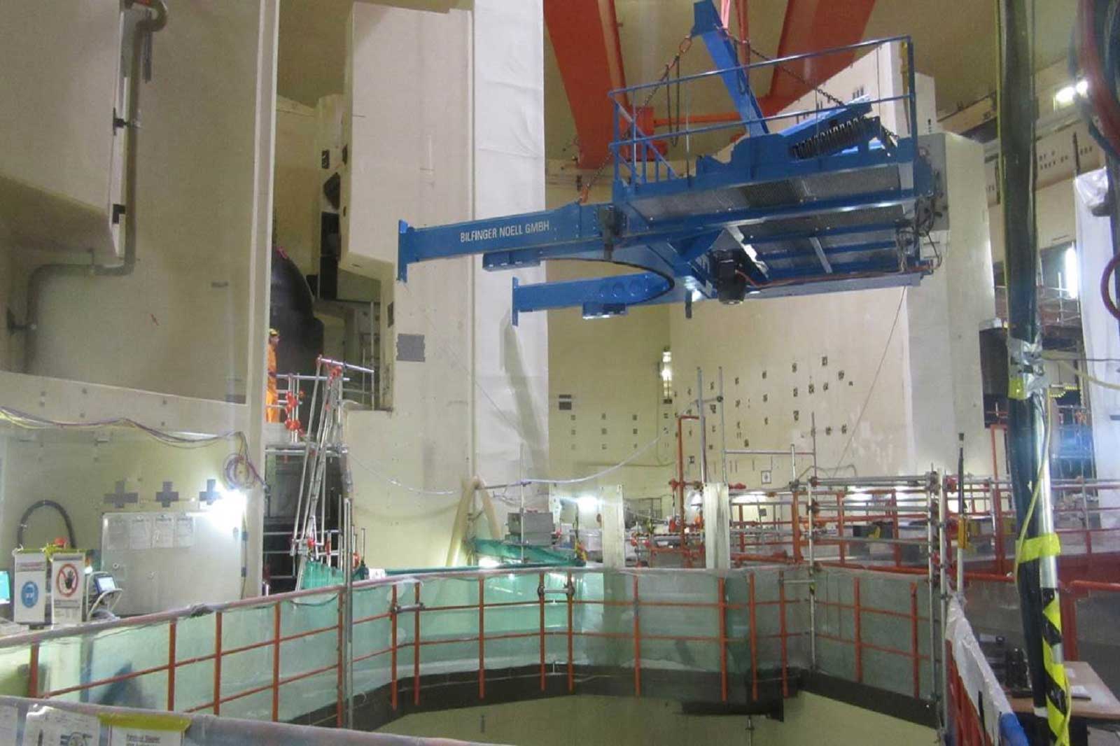 Ein Industriegebiet mit einem großen blauen Kran, Gerüsten und sichtbaren Baumaschinen in einer Einrichtung.