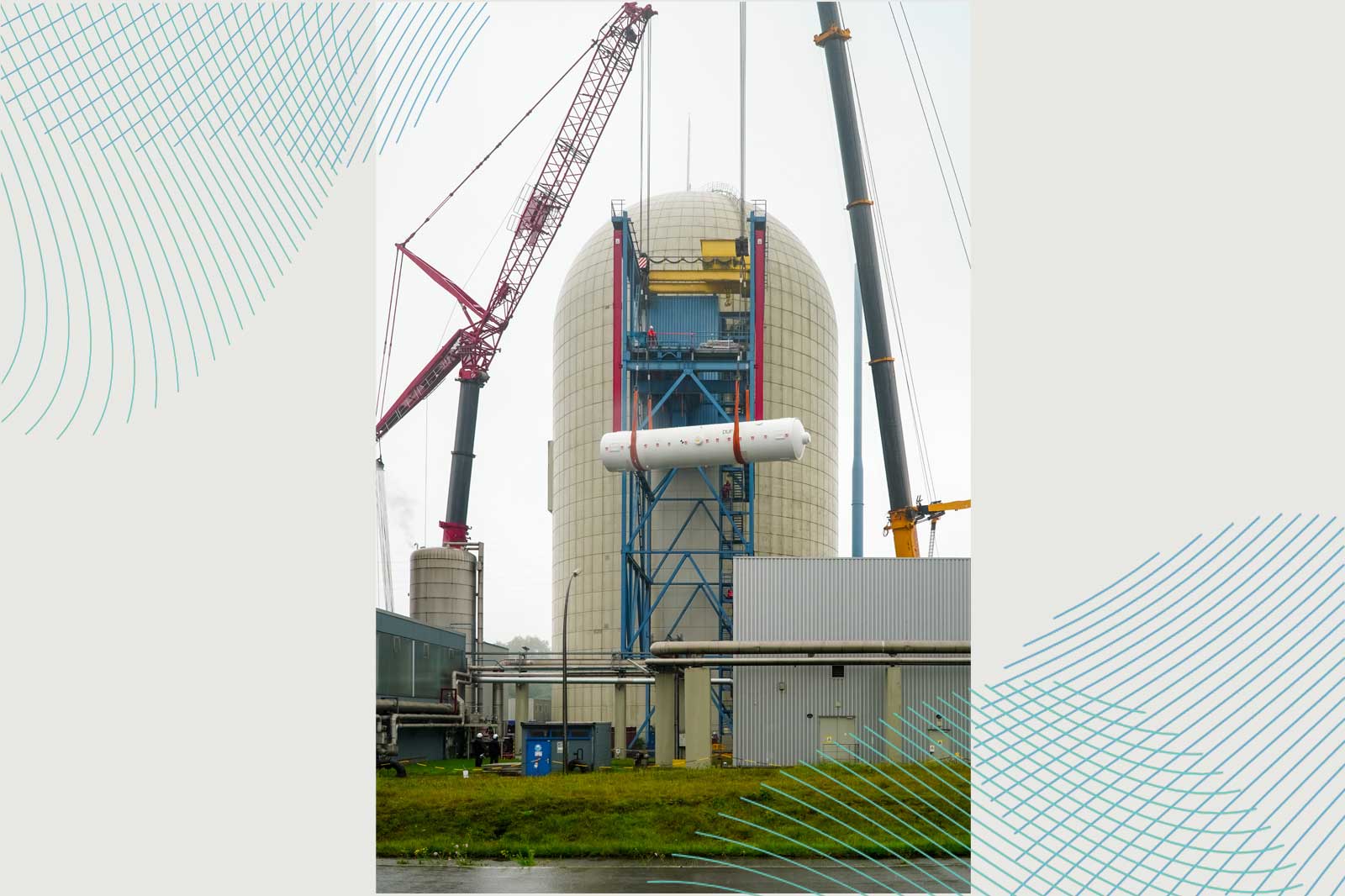 Eine große Industrieanlage mit Kränen, die ein weißes zylindrisches Objekt in Richtung eines siloförmigen Turms unter einem bewölkten Himmel heben.