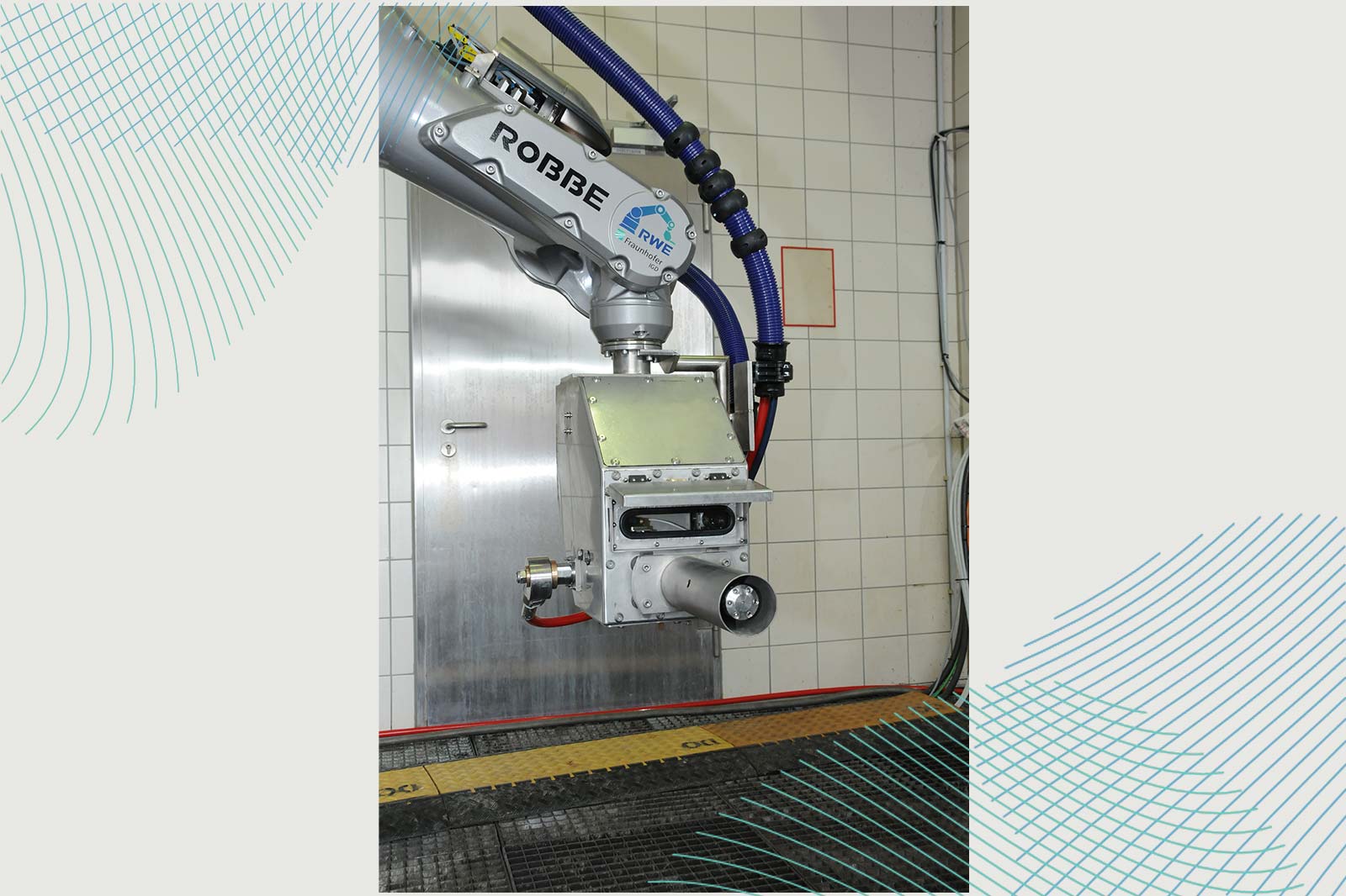 Ein als 'ROBBE' gekennzeichneter Roboterarm ist an einer Wand montiert und verfügt über eine Düse sowie mehrere angeschlossene Schläuche.