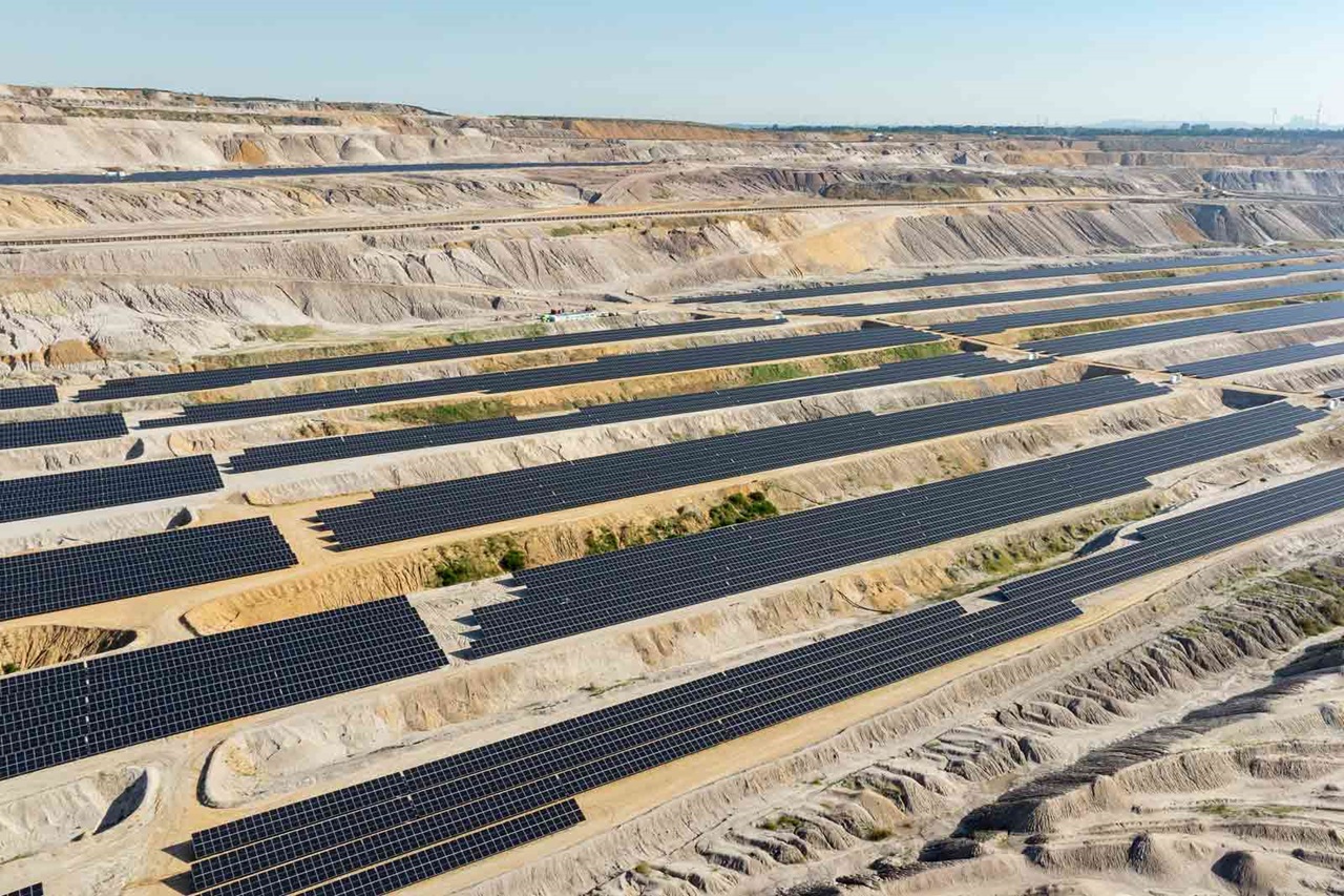 Aerial view of a solar farm with rows of solar panels set in a sandy landscape.