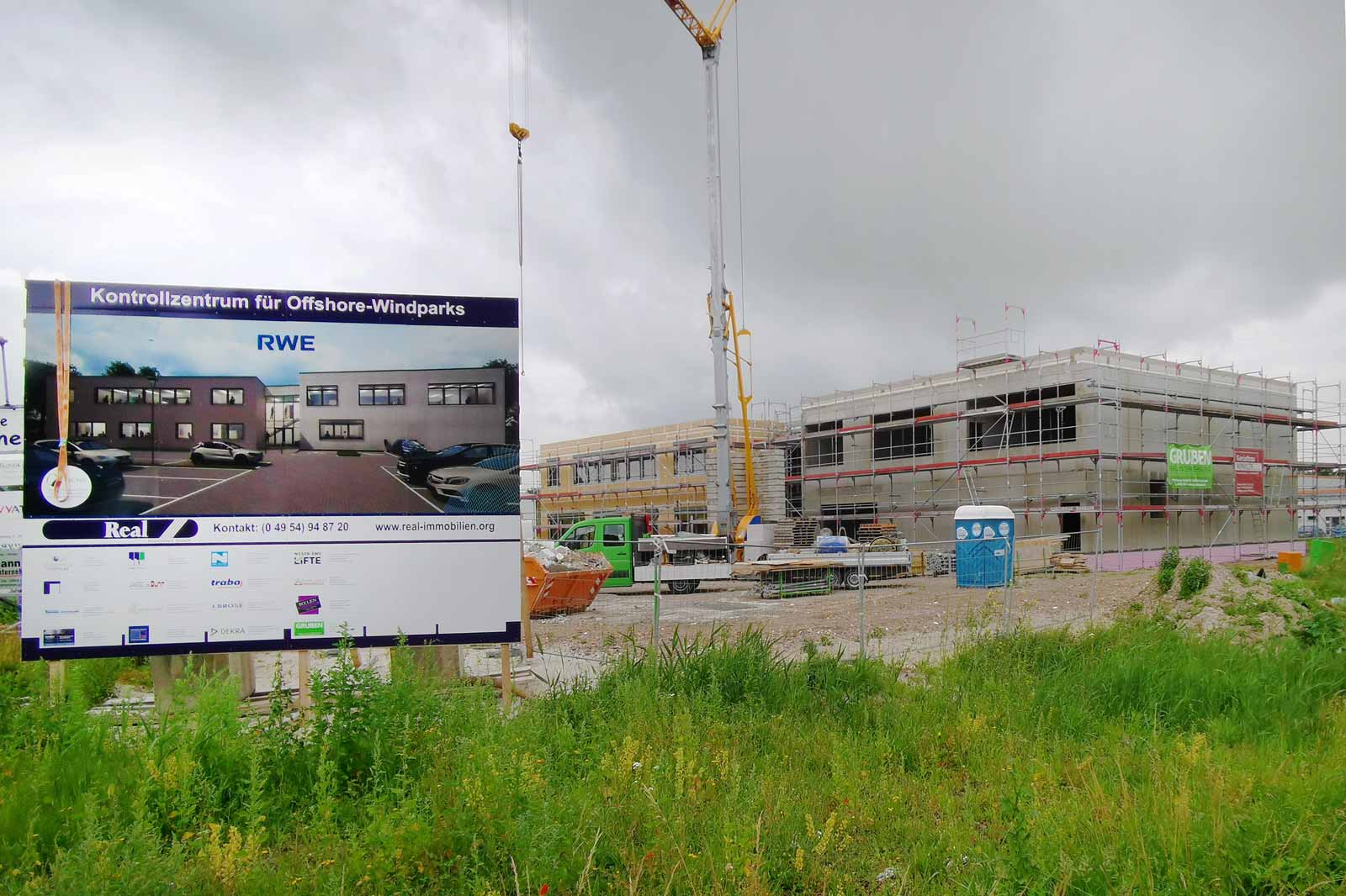 Bau eines Kontrollzentrums für Offshore-Windparks mit Baustelle, Anzeige und Kran im Hintergrund.