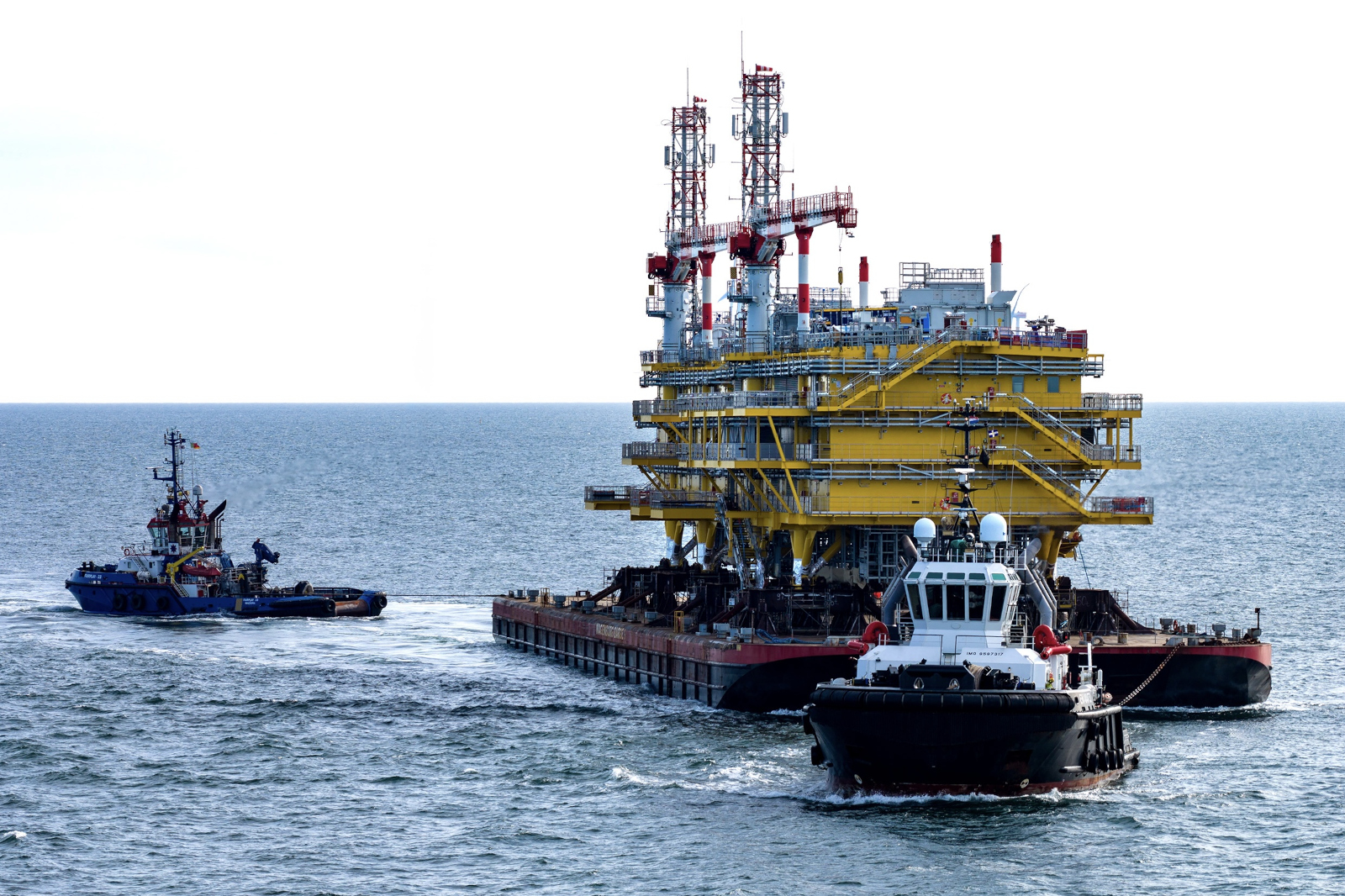 Gelbes Offshore-Plattformmodul auf Ponton von zwei Schleppern gezogen.