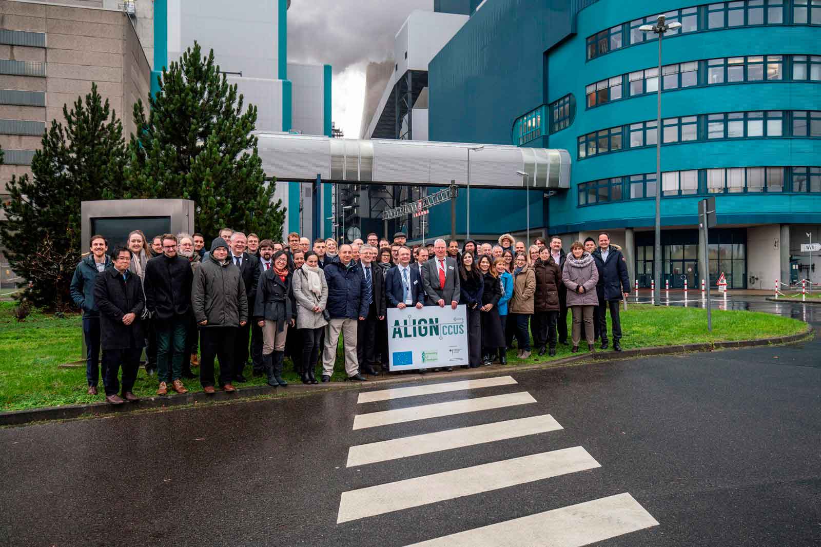 Gruppenfoto von Personen vor einem modernen Gebäude mit einem Grünen und einer Tafel zur CCUS-Initiative.