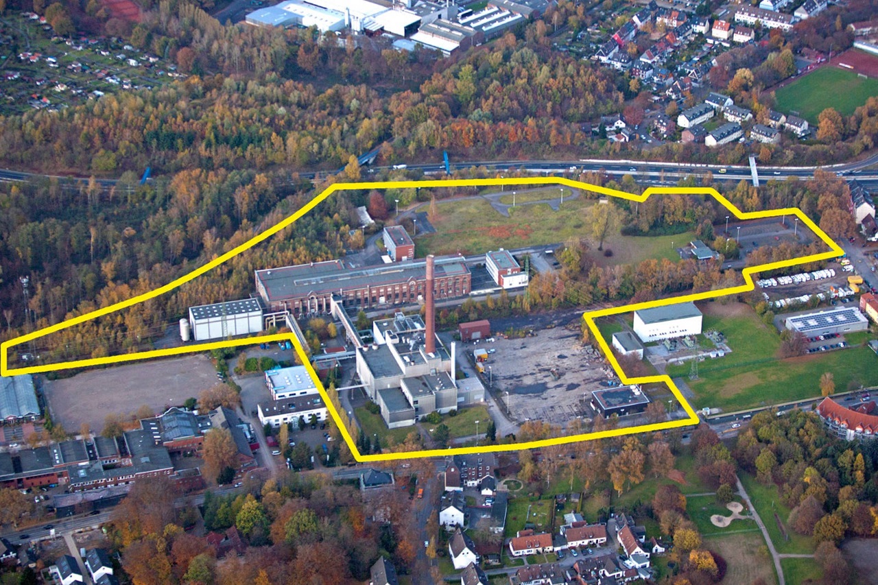 Luftaufnahme eines Industriegebiets mit Fabriken und Bäumen, umrandet von einer gelben Linie.