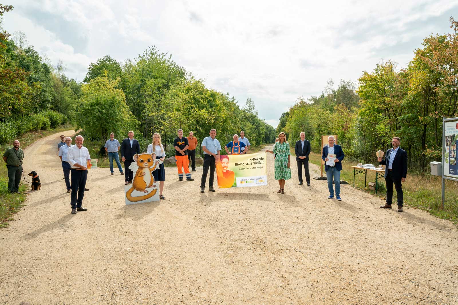 Eine Gruppe von Menschen steht auf einem Weg im Wald und hält ein Banner zur UN-Dekade für biologische Vielfalt.