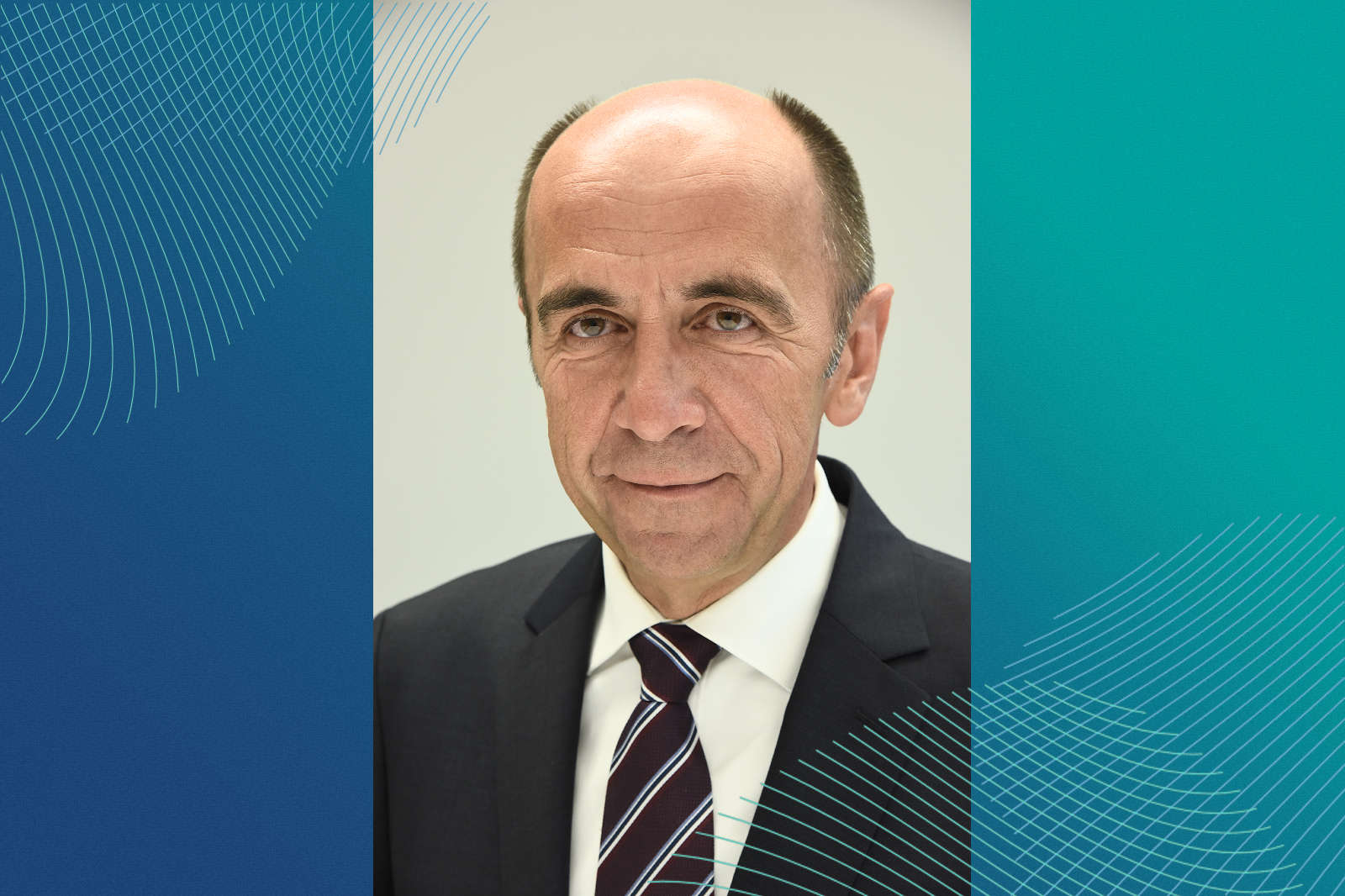 Ein Mann in einem Anzug mit einer Krawatte steht vor einem simplen Hintergrund. Die linke Seite hat eine blaue Farbverlauftextur.