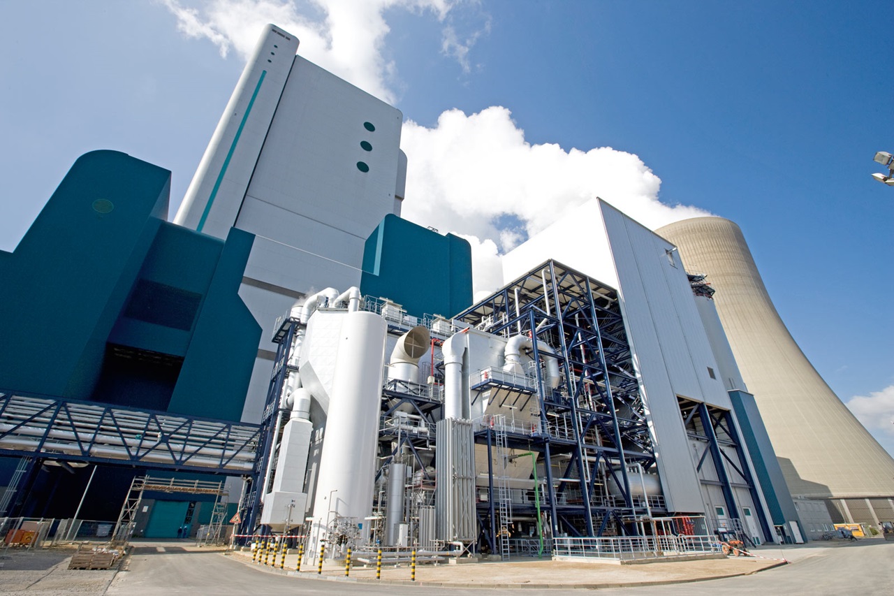 Eine moderne industrielle Anlage mit Kühltürmen, Maschinen und einem klaren blauen Himmel.