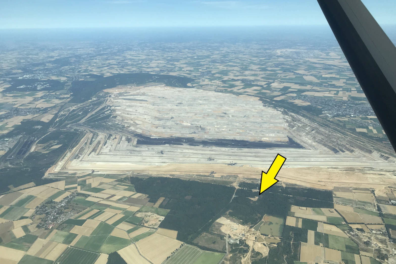 Luftaufnahme eines großen, ausgegrabenen Gebiets, umgeben von landwirtschaftlichen Flächen und Wäldern.