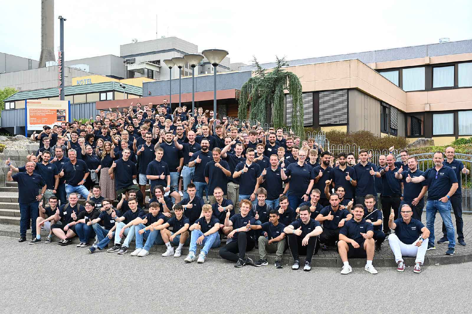 Eine große Gruppe von Menschen in navyblauen T-Shirts, die draußen zusammen posieren und fröhlich aussehen.