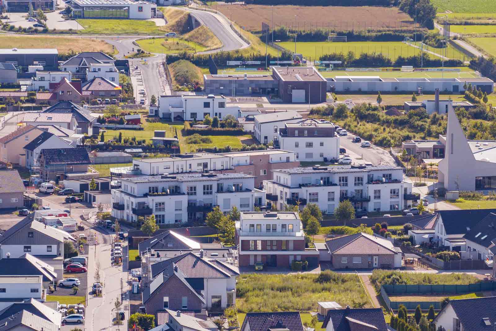 Eine Luftaufnahme eines Wohngebiets mit verschiedenen Häusern, modernen Gebäuden und Grünflächen.