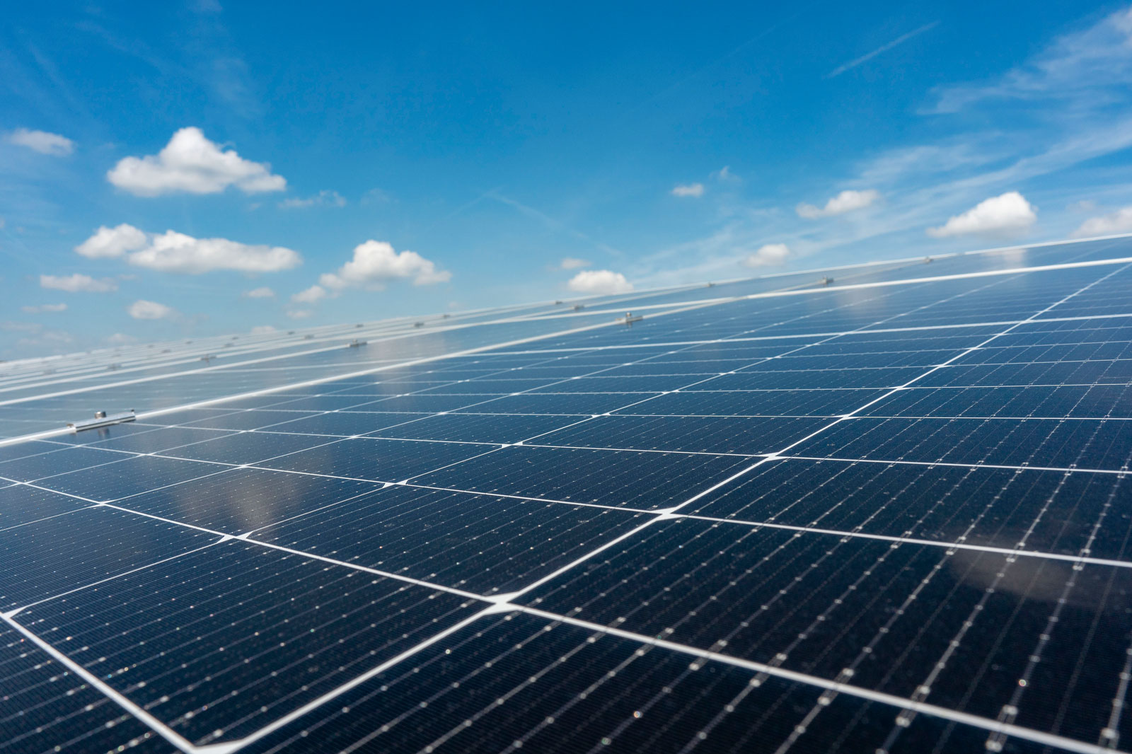 A solar panel field displaying dark solar panels under a clear blue sky.