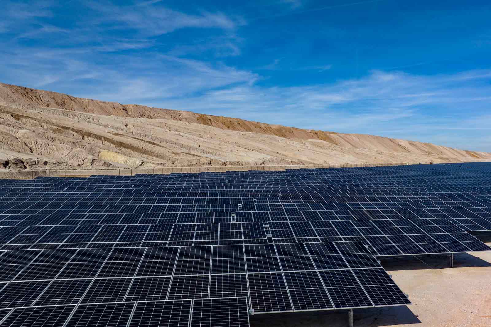 Ein großes Solarpanelfeld in einer Wüstenlandschaft unter einem klaren blauen Himmel.