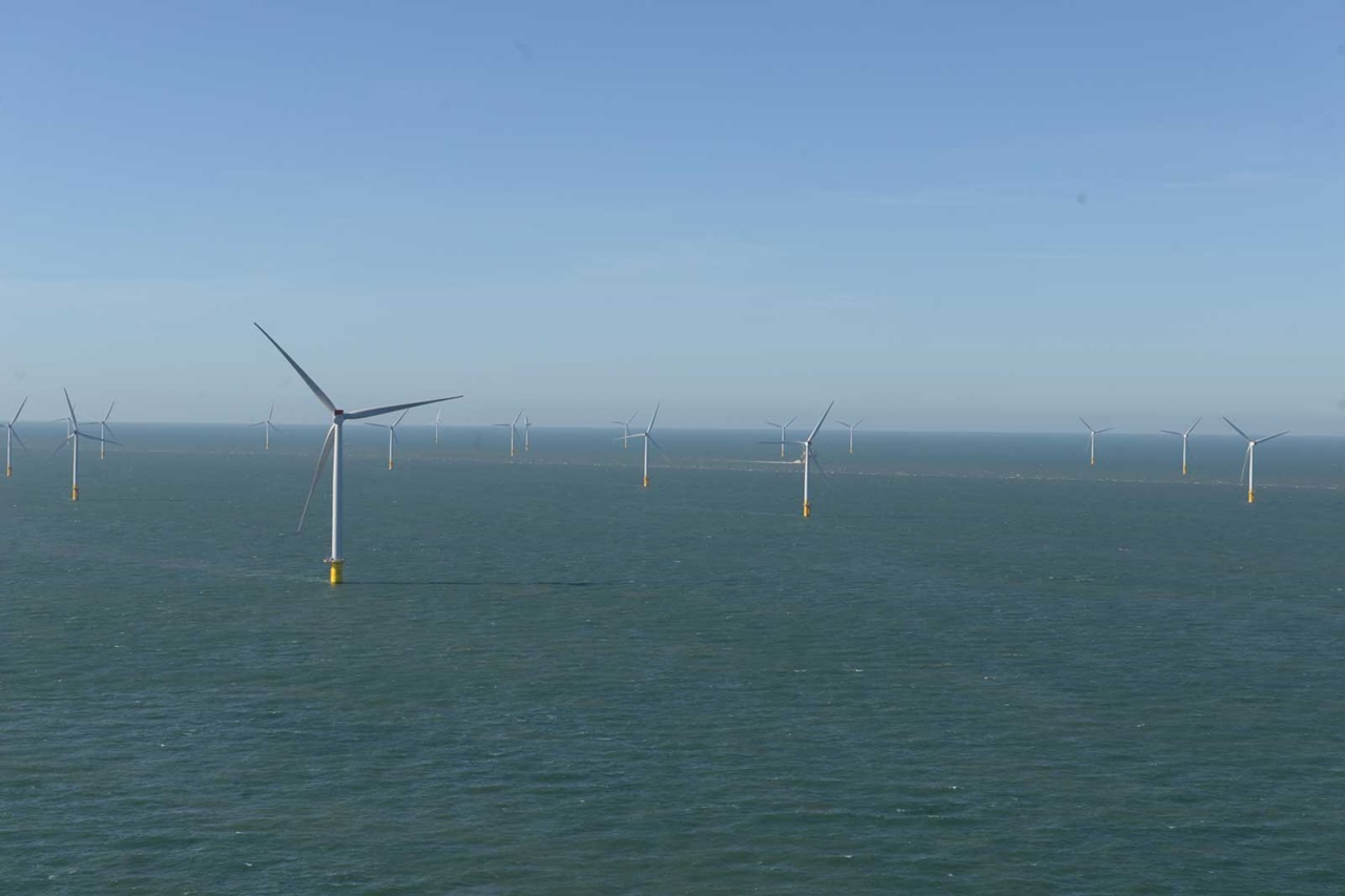 Several wind turbines are positioned in the sea against a clear blue sky backdrop.