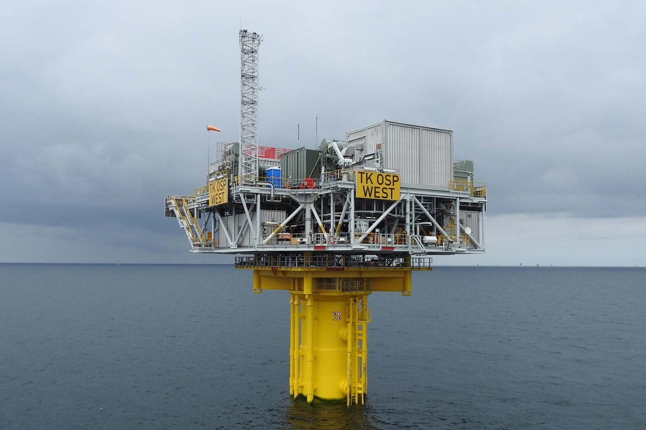Ölplattform in der Nordsee. Gelbe Basis, graue Struktur und Wolken im Hintergrund.