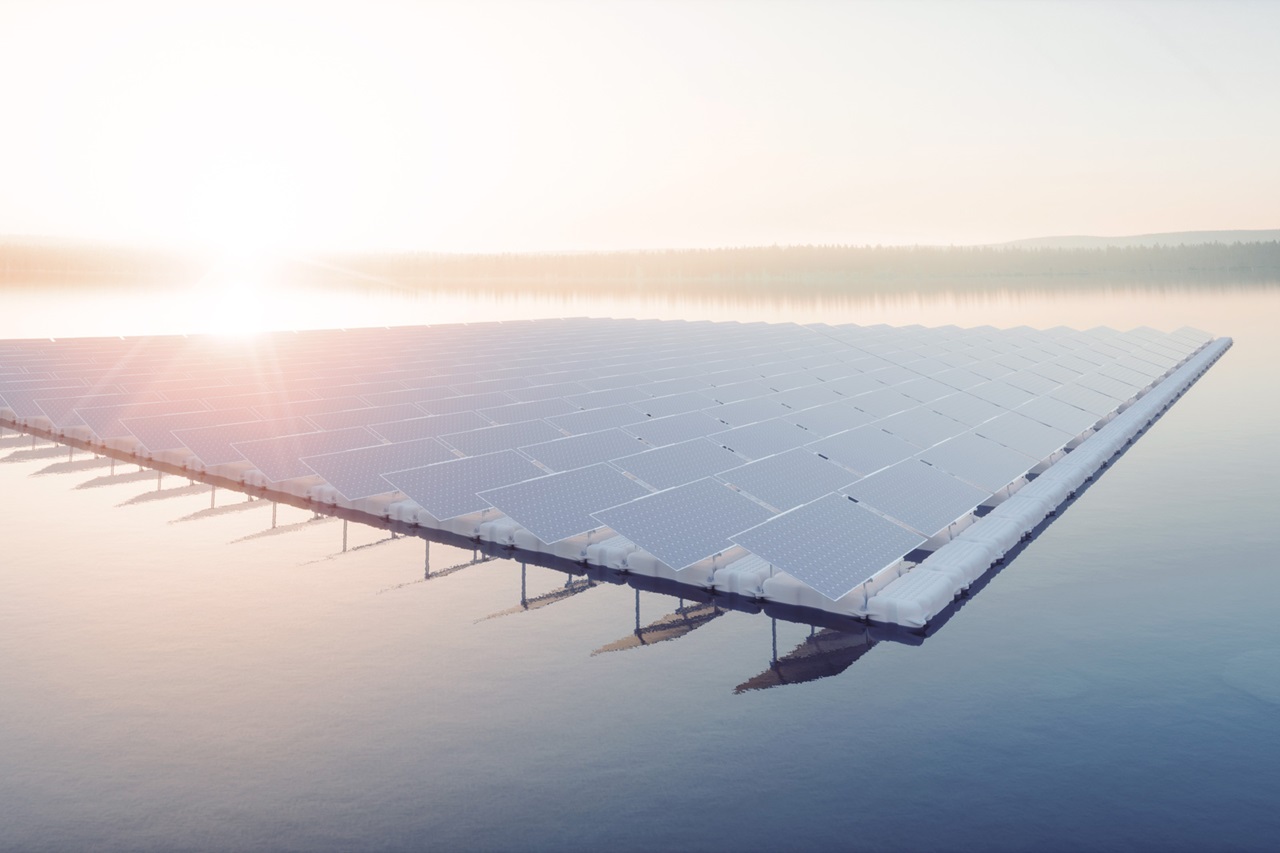 Floating solar panels on calm water at sunrise, surrounded by mist.