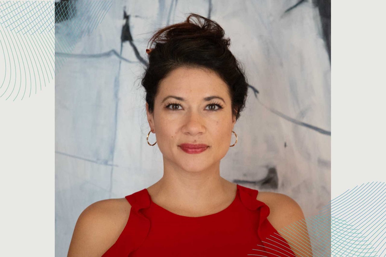 A person wearing a red top with ruffles stands against an abstract background.