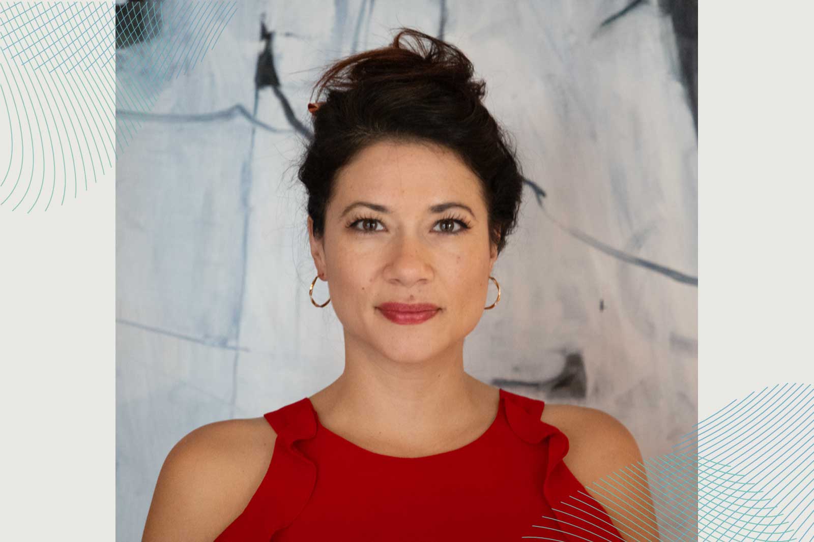 A person wearing a red top with ruffles stands against an abstract background.