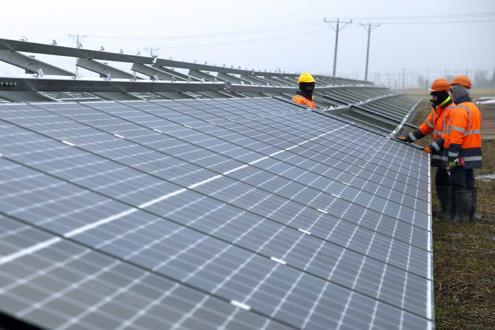 Workers install solar panels in a field, contributing to sustainable energy production.