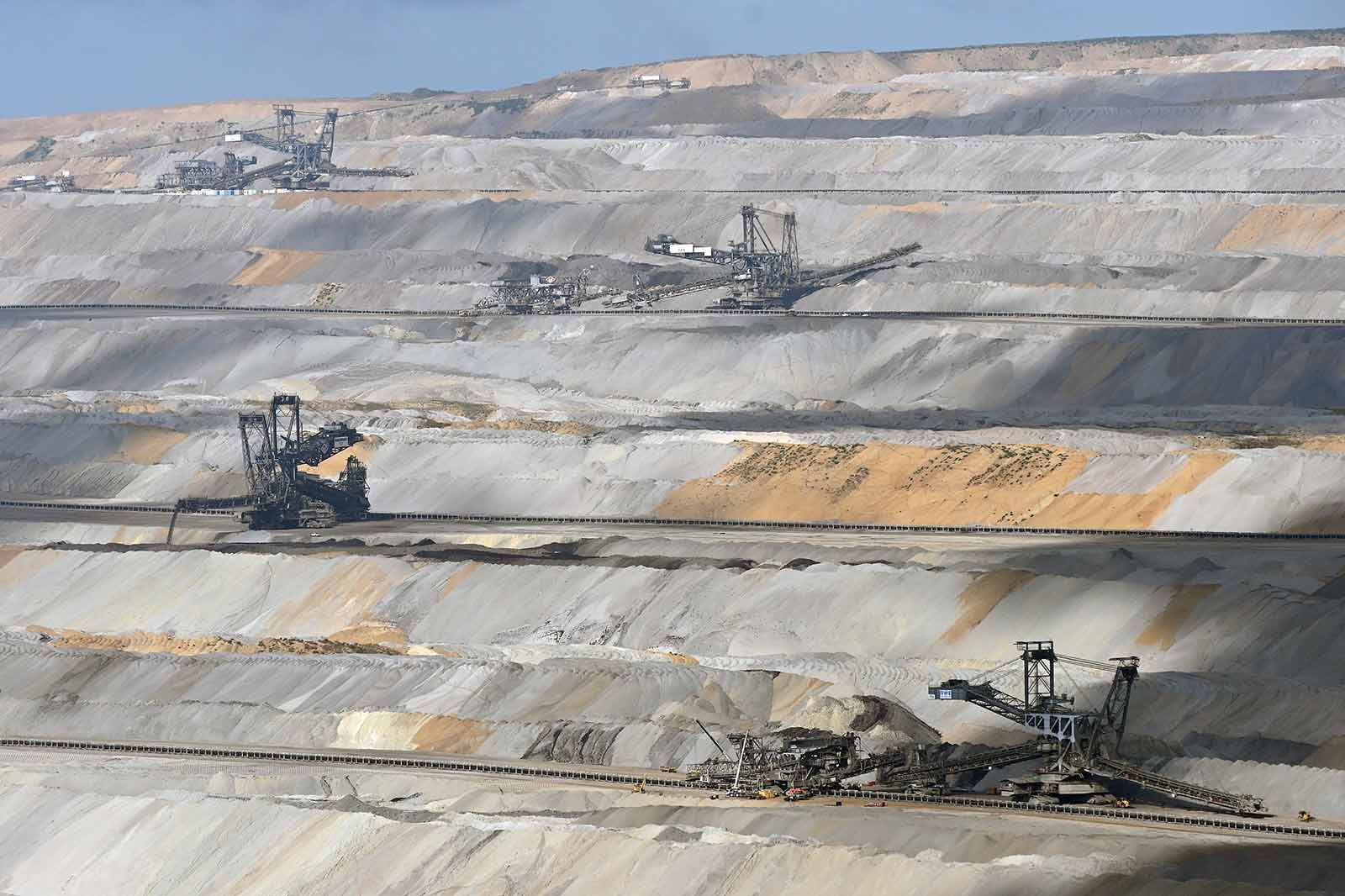 Luftaufnahme eines großen Bergwerks mit riesigen Maschinen, die Ressourcen aus geschichteten Erde und Felsen abbauen.