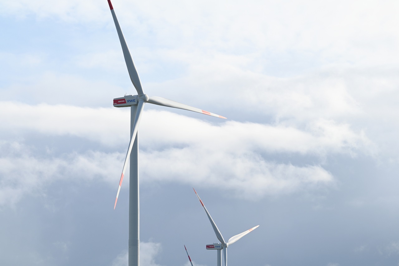 Drei Windkraftanlagen vor einem bewölkten Himmel, die saubere Energietechnologie und Umweltbewusstsein zeigen.