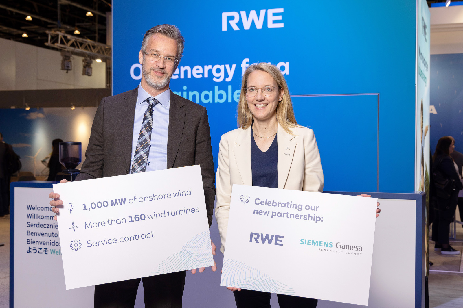 Zwei Fachleute halten Partner-Schild, mit Informationen über Windenergie und neue Zusammenarbeit zwischen RWE und Siemens Gamesa.