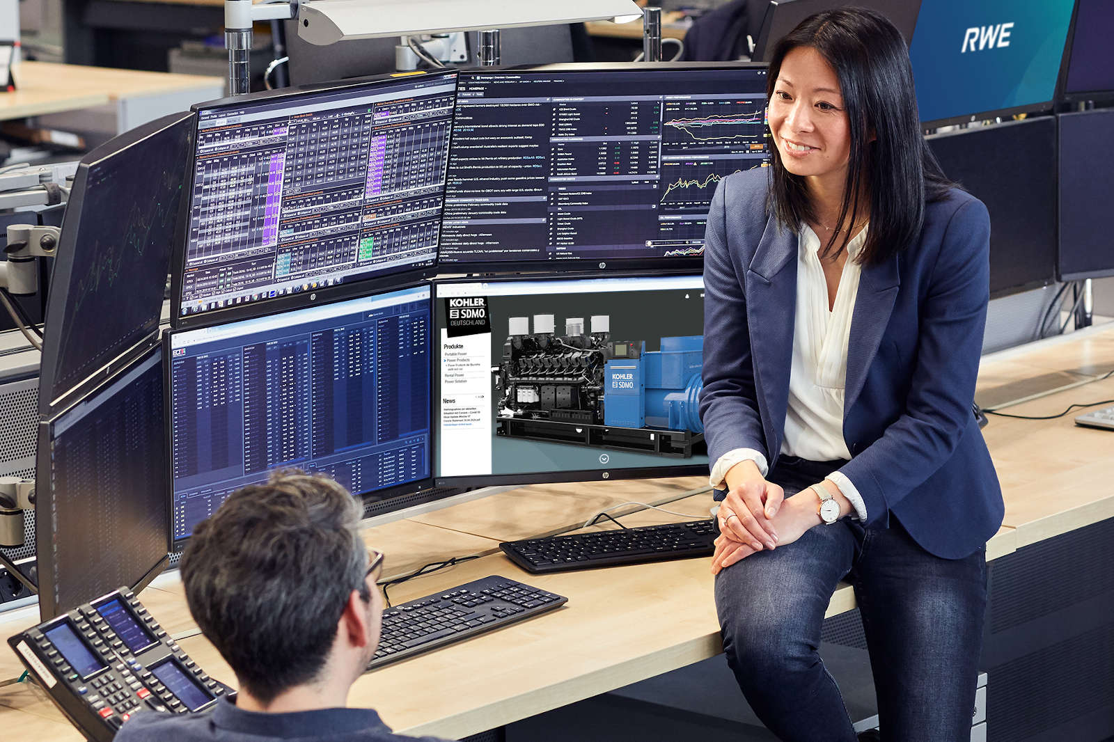 A person sits at a table with multiple monitors displaying financial data and technical information.
