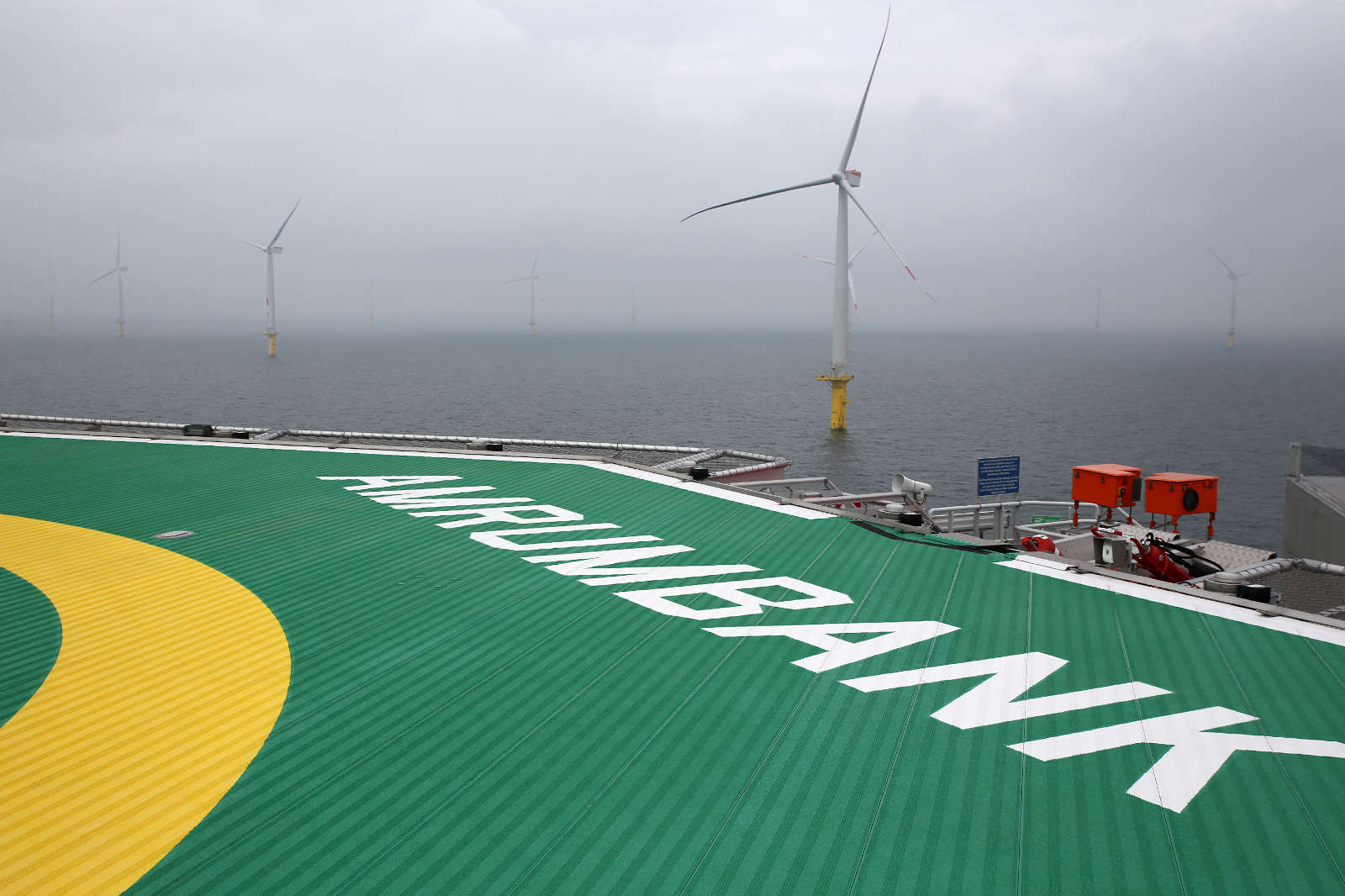 Blick auf die Offshore-Plattform mit Windkraftanlagen im Nebel. Auf dem Boden steht 'AMRUMBANK'.
