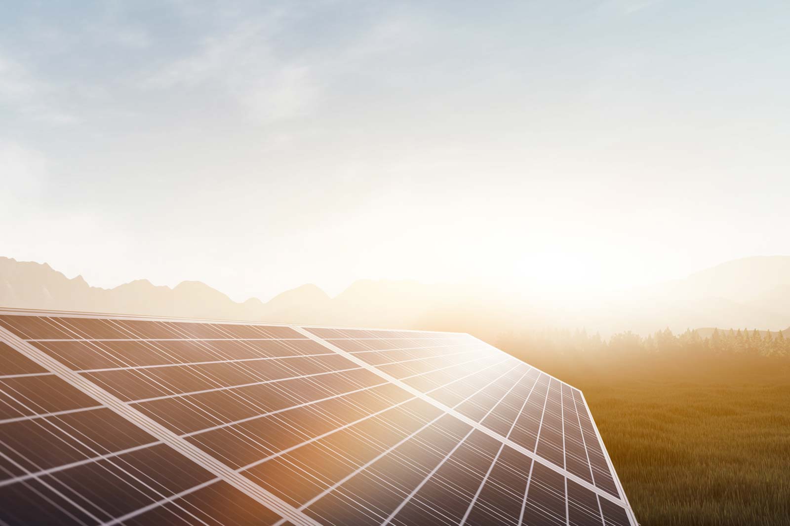Solar panels at sunset, with mountains and forests in the background.