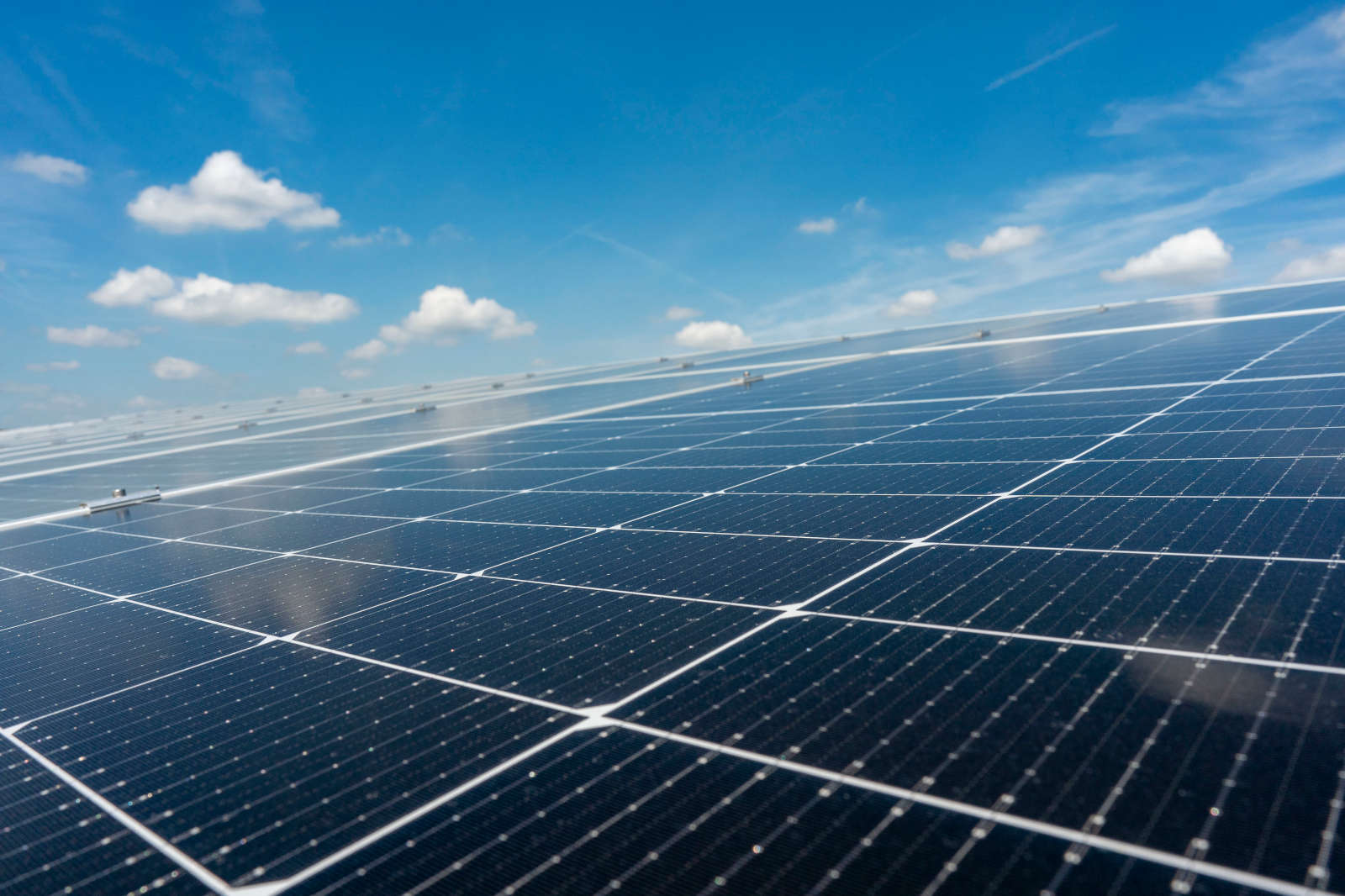 Ein sonniger Himmel mit einigen Wolken über einem Solarpanel, das Sonnenlicht einfängt.