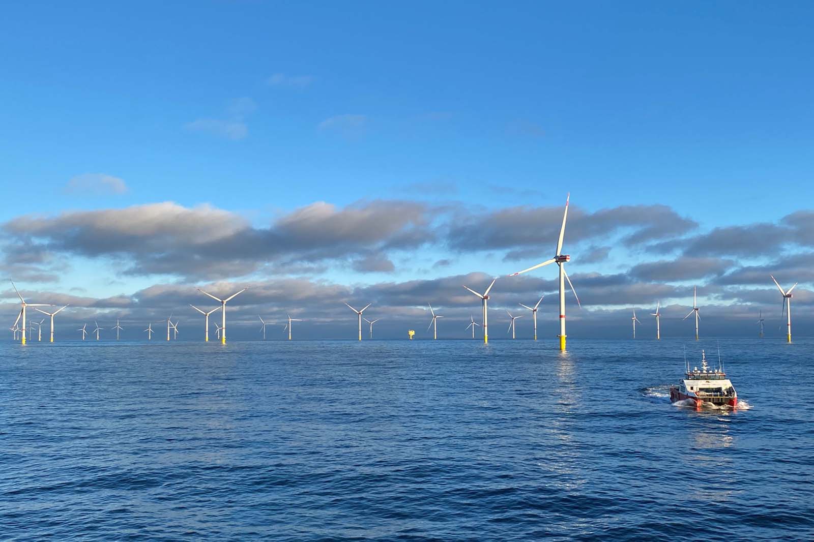Offshore Windturbinen über ruhiger See mit Serviceboot und Boje
