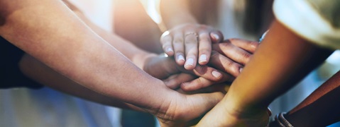 Vereinte Hände in einem Kreis, die Zusammenarbeit und Gemeinschaft symbolisieren.