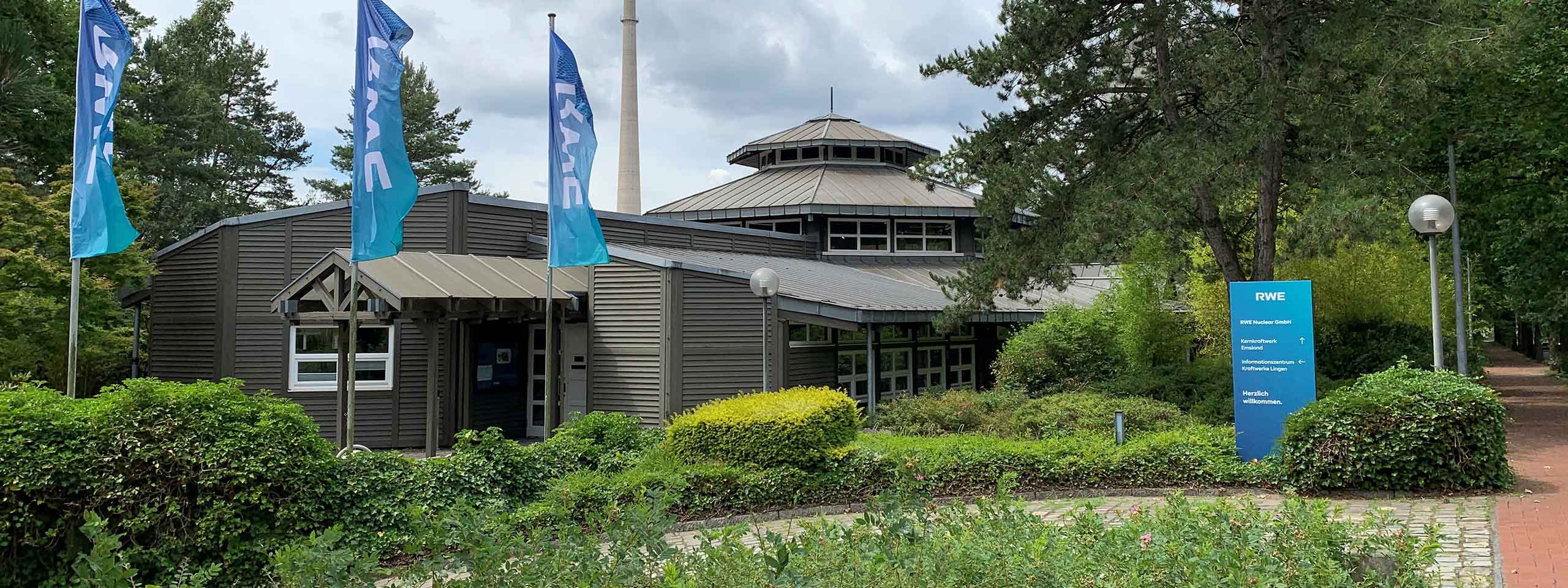 Ein Informationszentrum mit umgebender grüner Vegetation, Fahnen und einem Gehweg in einer natürlichen Umgebung.