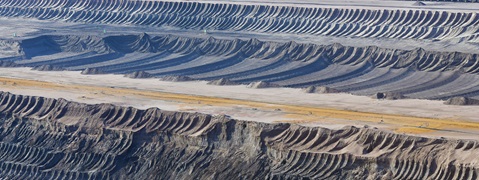 Eine landschaftliche Ansicht eines Abbaugebiets mit gewellten Erdwällen und einem breiten, leeren Boden im Vordergrund.