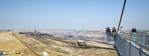 Ein Panoramablick auf einen Tagebau mit Besuchern auf einer Aussichtsplattform, die Fotos machen.