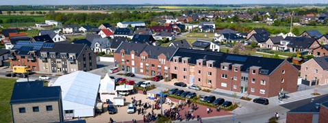 Luftaufnahme eines Wohngebiets mit modernen Häusern und einer Veranstaltung im Freien.