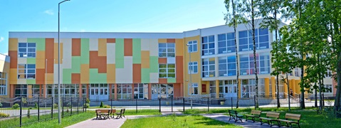 Ein modernes Schulgebäude mit bunten Fassaden und großen Fenstern, umgeben von einem gepflegten Garten.