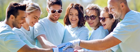 Eine Gruppe von Menschen in hellblauen T-Shirts, die gemeinsam eine Aktivität im Freien durchführen und zusammenarbeiten.