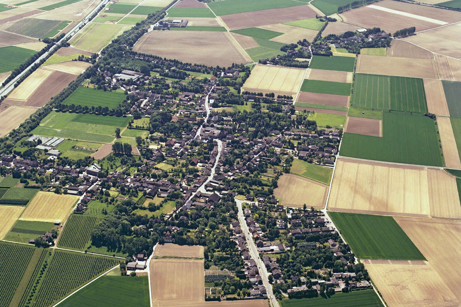 Luftaufnahme eines Dorfes umgeben von verschiedenen landwirtschaftlichen Feldern und Ackerland.