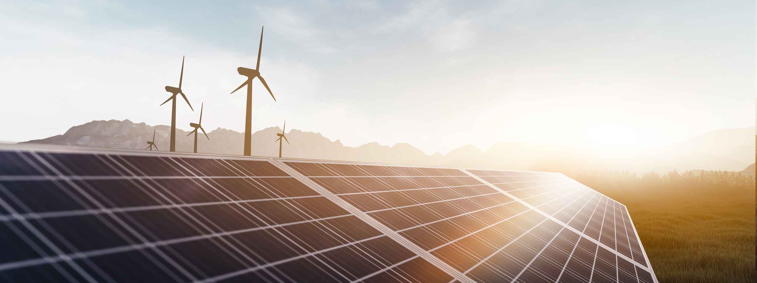 Solarpaneele im Vordergrund mit Windturbinen im Hintergrund und einer sanften Landschaft unter einem klaren Himmel.