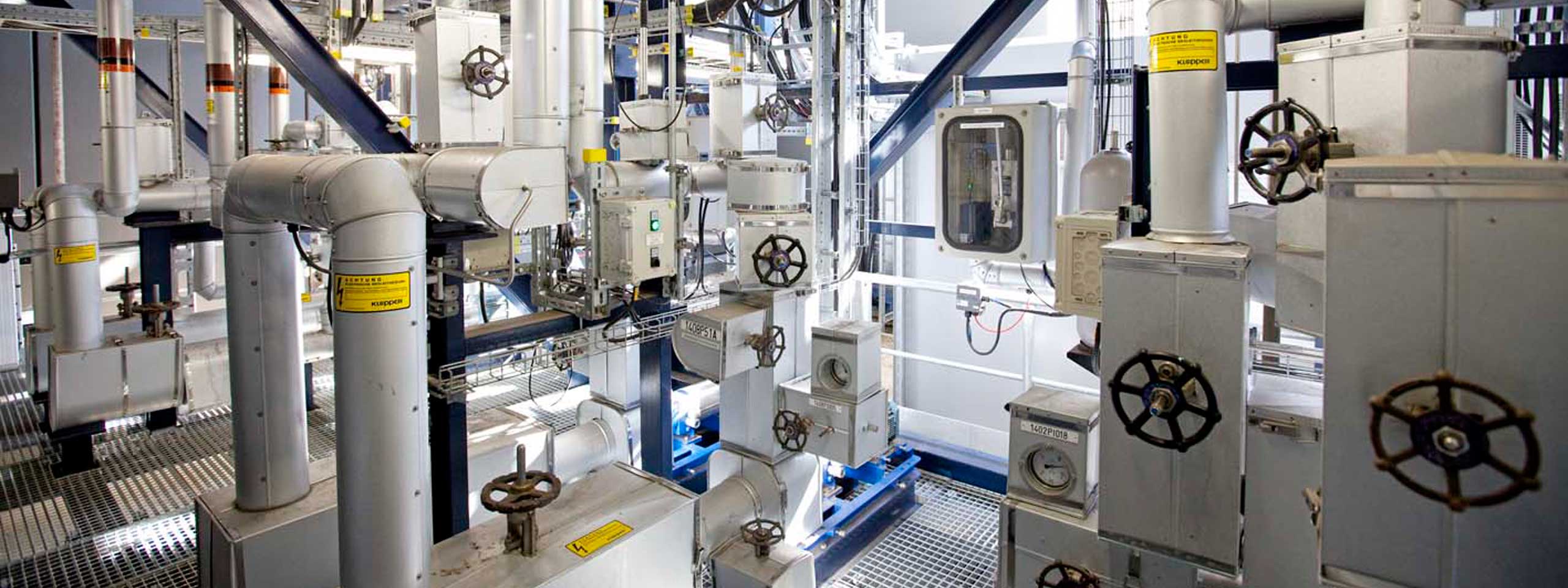 Eine komplexe Anordnung von Rohren und Ventilen in einer Industrieumgebung. Die Rohre sind aus Metall und gut strukturiert.