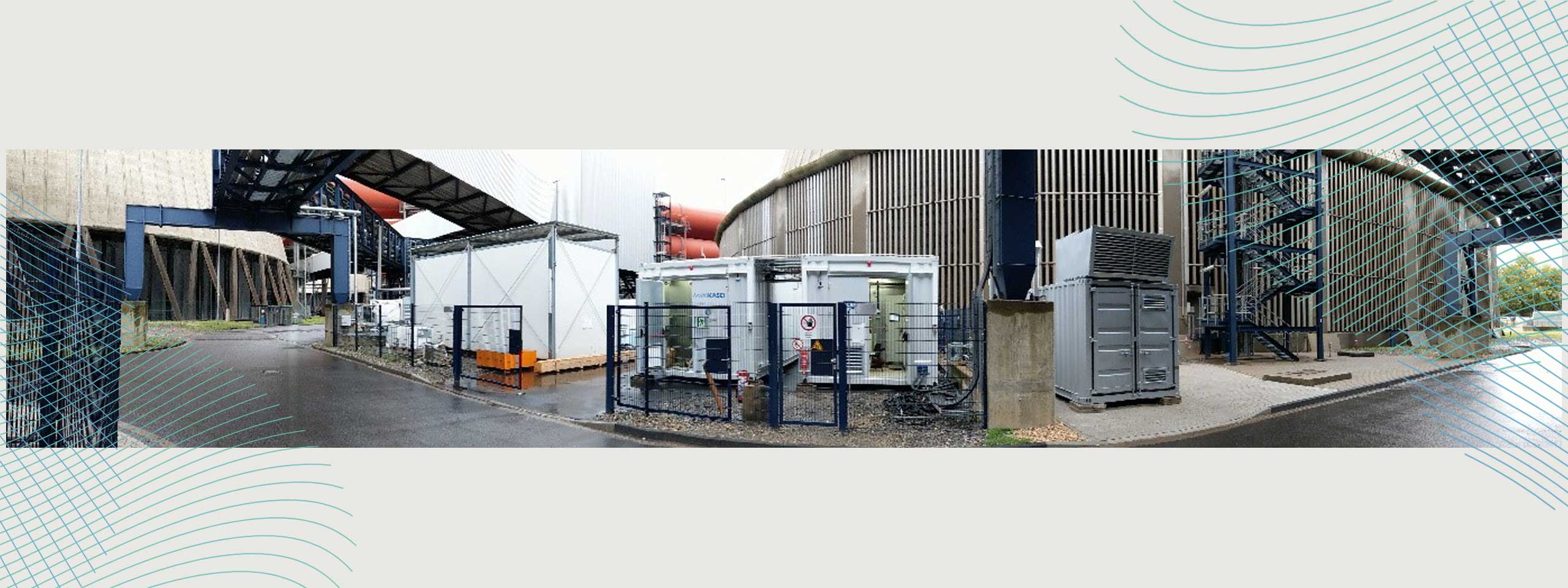 Eine industrielle Umgebung mit mehreren Containern, Zäunen und einem Außengelände neben großen Gebäuden.