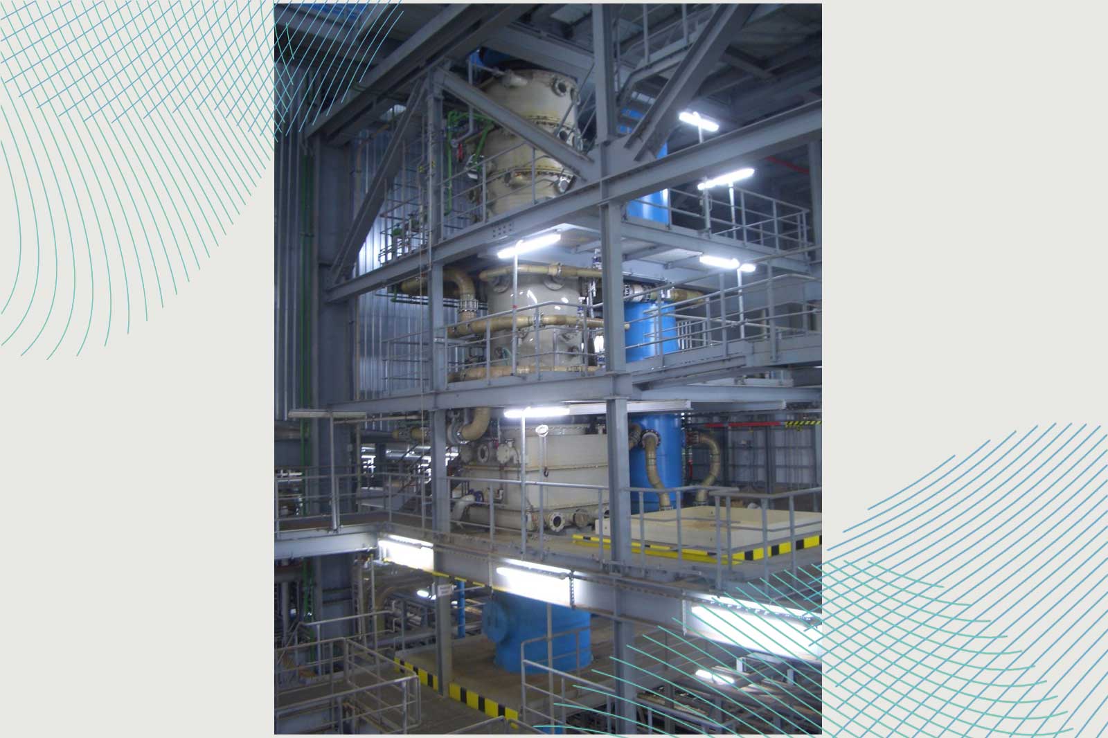 Eine Ansicht einer Industrieanlage mit Maschinen, Rohren und Plattformen, beleuchtet von Deckenlichtern.