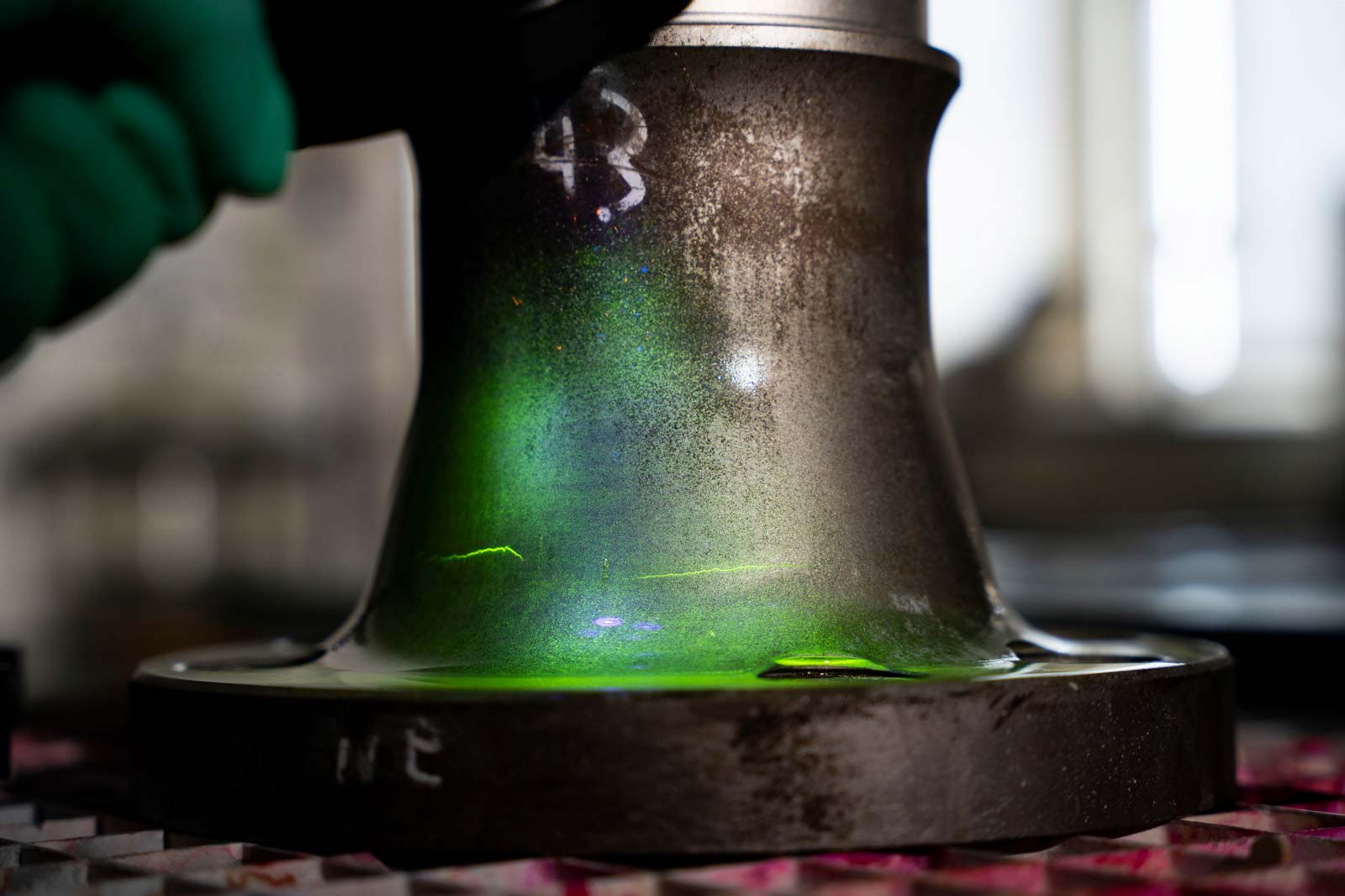 Eine metallene Oberfläche mit grünem Lichtreflexionsmuster und einem Handgriff. Saubere Laborumgebung.