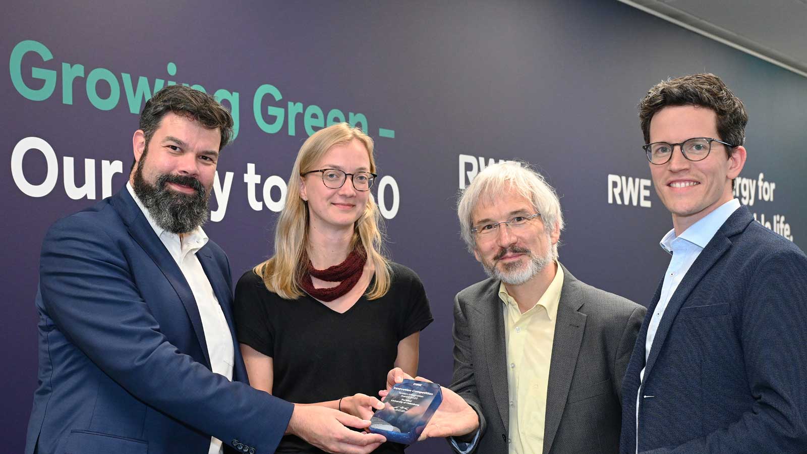 Eine Gruppe von vier Personen hält einen Preis und steht vor einer Wand mit dem Text "Growing Green - Our way to 2030".