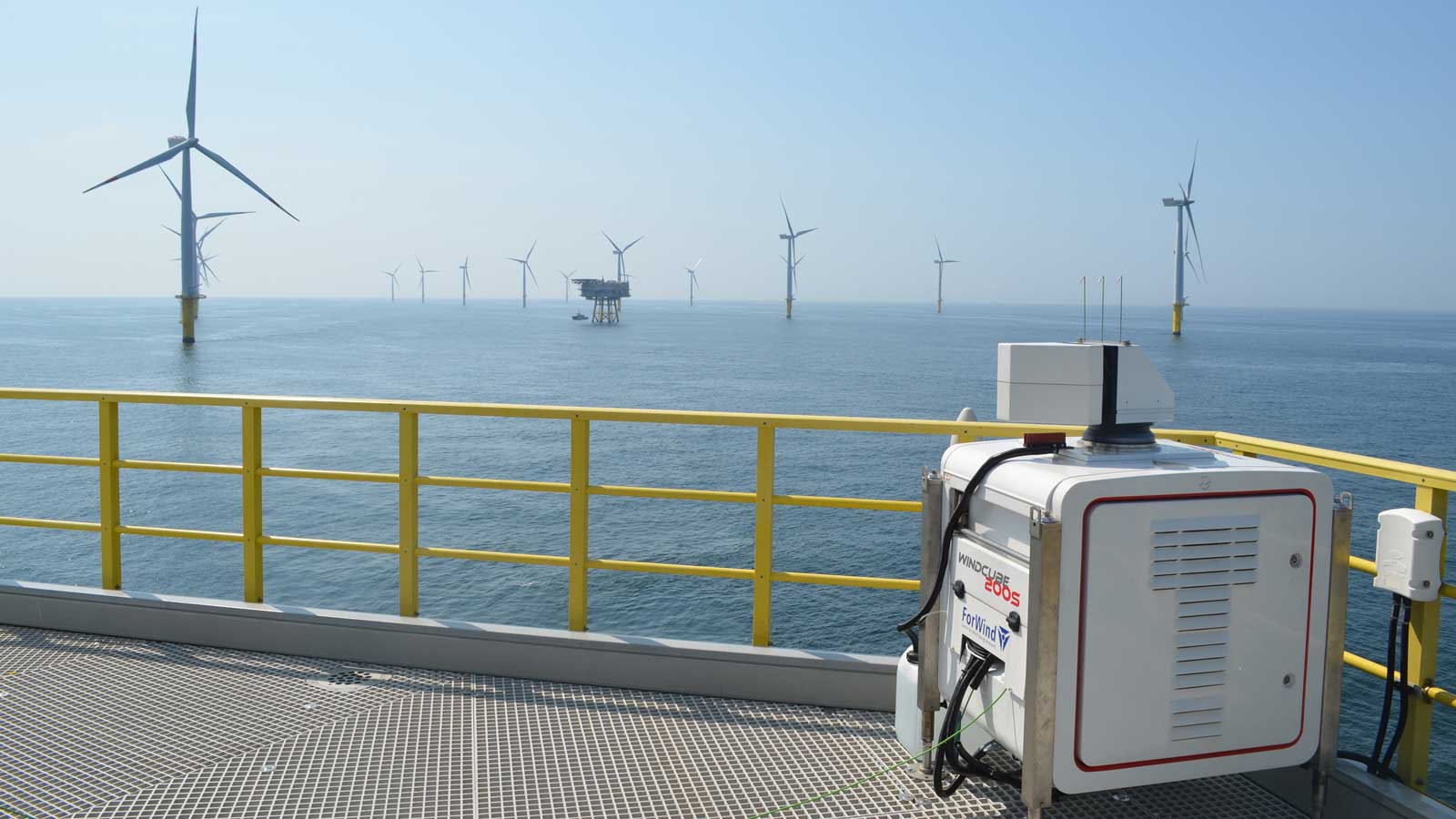 Ein Blick auf Offshore-Windturbinen von einer Plattform aus, mit blauem Meer und Himmel im Hintergrund.