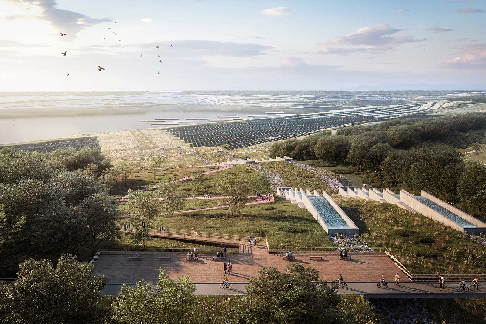 Blick auf eine Küstenlandschaft mit breiter Promenade, Radfahrern und Spaziergängern, gestuften Wasserbecken, Vegetation und entfernten Salzwiesen.