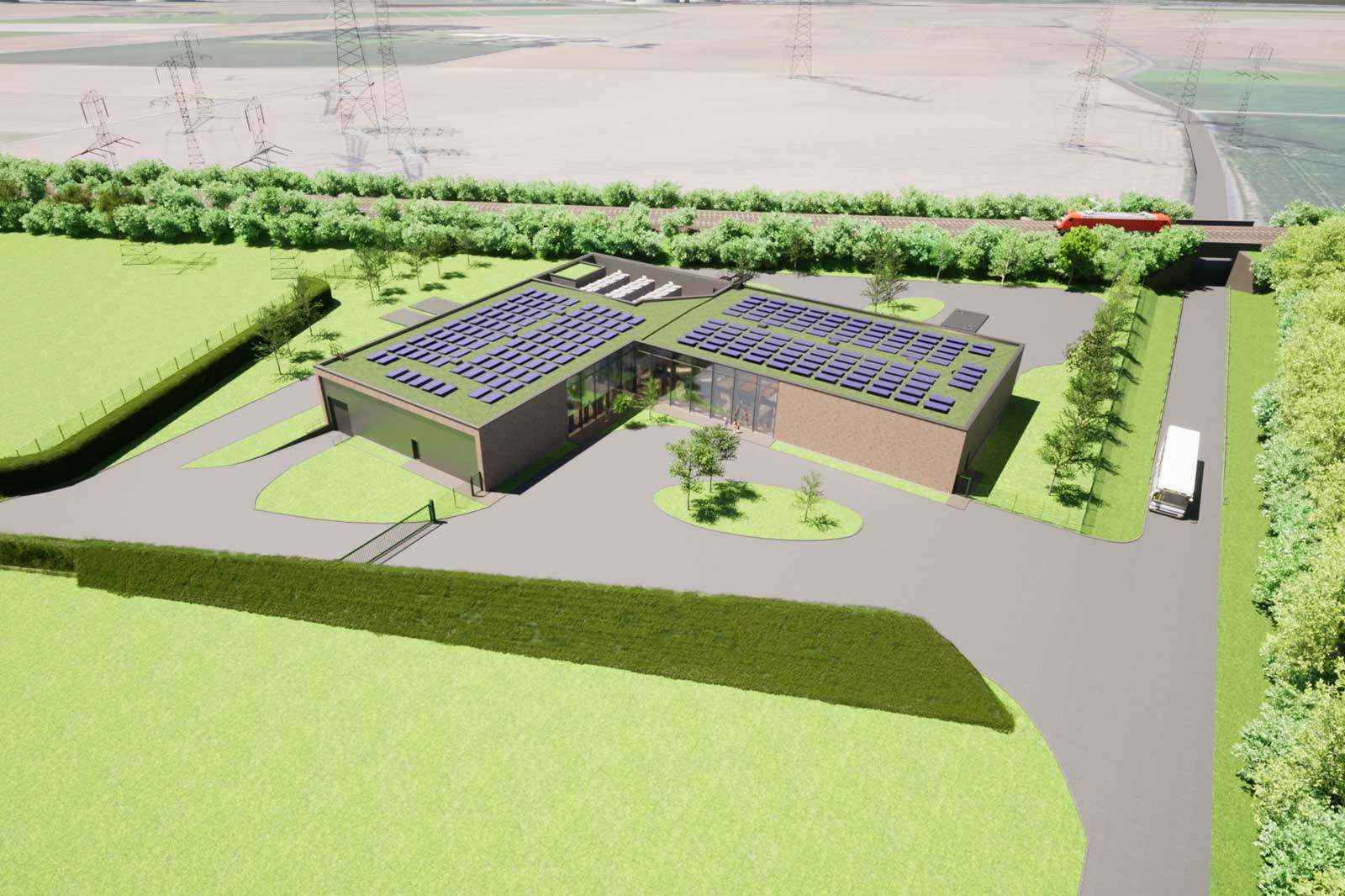 L-förmiges Backsteingebäude mit Glas-Eingang und zahlreichen Solarpaneelen auf dem Dach, umgeben von Zufahrt, Hecken, Strommasten und einem Zug.